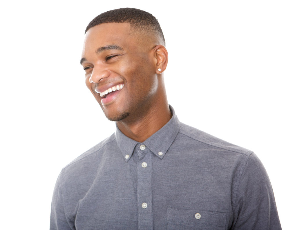 Close up portrait of a handsome young black man laughing on isolated white background